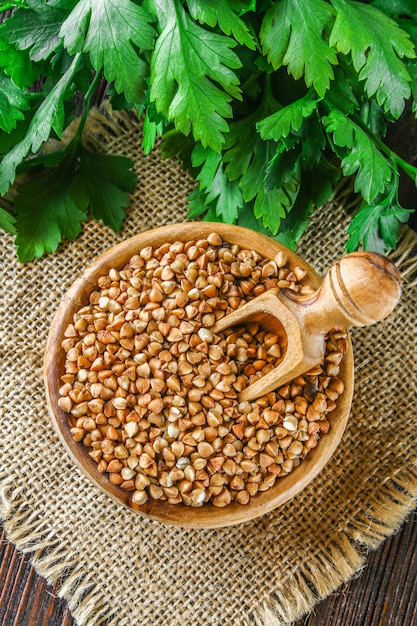 Sarrasin cru dans des bols en bois et une boule sur un sac sur un fond en bois. Alimentation saine