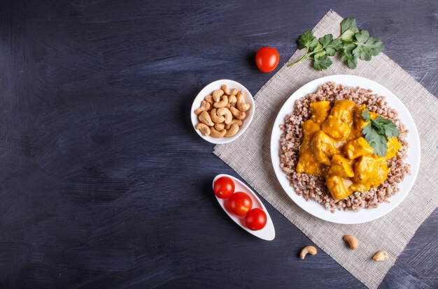 Sarrasin Avec Sauce Au Poulet Au Curry Et Noix De Cajou Sur Une Surface En Bois Noire.