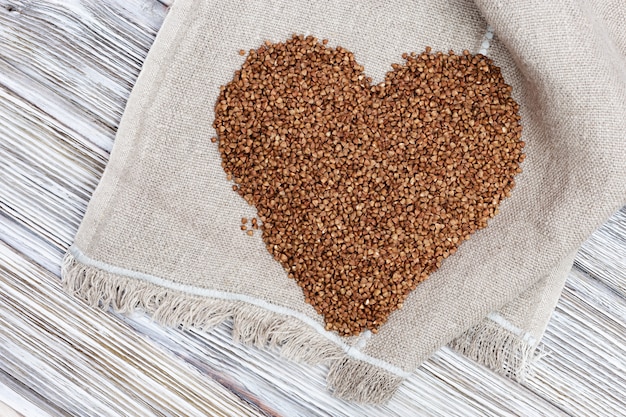 Photo sarrasins éparpillés en forme de coeur sur une table en bois avec un sac.