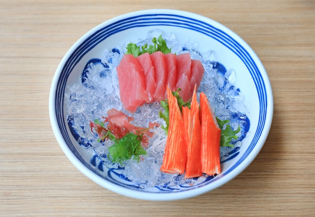 Sashimi au thon servi avec des bâtonnets d'algues et de crabe sur la glace.