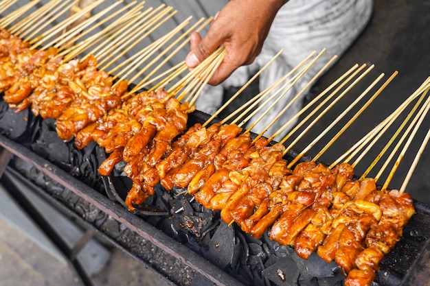 Saté de poulet grillé au feu de charbon de bois traditionnel. brochettes de viande brûlées par la fumée