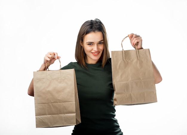 Satisfait adulte femme portant des sacs en papier après avoir fait des achats sur blanc