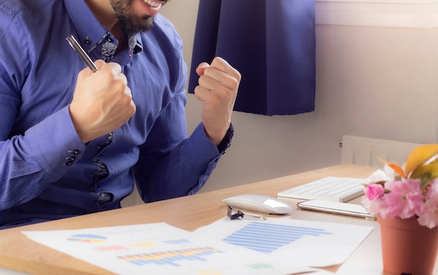 Photo satisfait du travail accompli. heureux jeune homme travaillant sur un ordinateur portable assis dans son bureau