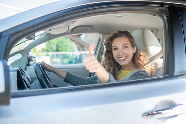 Satisfait femme souriante conduisant une voiture montrant ok