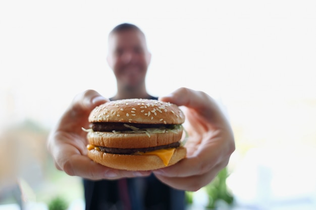 Satisfait de jeune homme tenant un hamburger