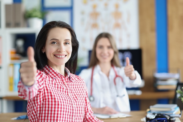 Satisfaite en bonne santé souriante jeune patiente adulte montrant le geste du pouce en l'air avec le médecin