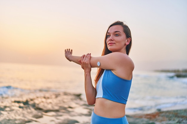 Satisfaite d'une femme patiente diabétique mince de remise en forme faisant des exercices d'étirement des mains au bord de la mer Habitudes saines et mode de vie actif du diabète sucré