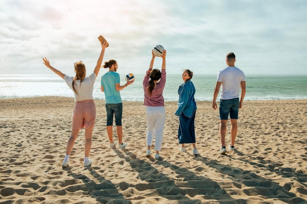 Satisfaits jeunes Arabes et Européens en casual avec des balles s'amusent regarder l'océan profiter de la liberté