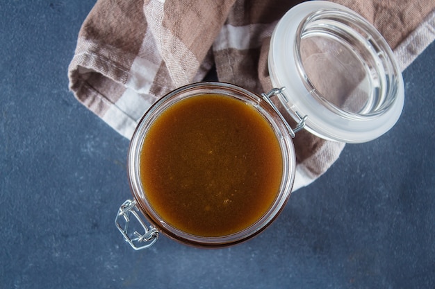 Sauce au caramel salé fait maison dans un bocal sur fond de table en béton bleu. Espace de copie, vue de dessus