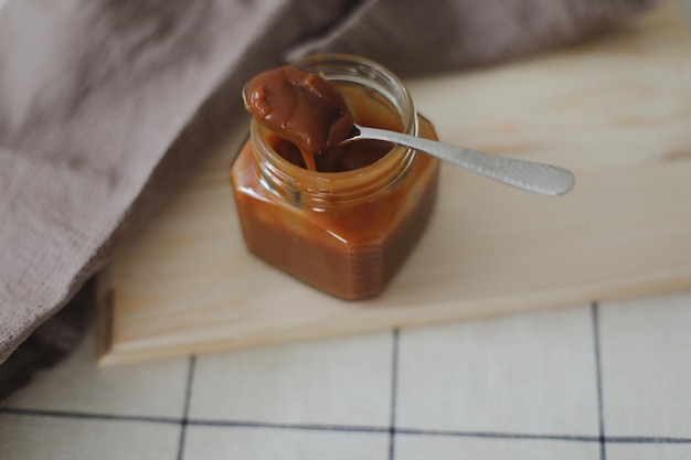 Sauce au caramel salé maison en pot sur table en bois rustique