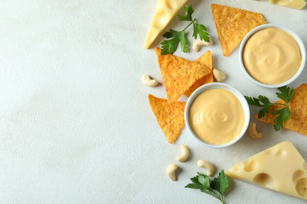 Sauce au fromage et collations sur une table texturée blanche