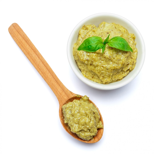 Photo sauce au pesto avec basilic et cuillère en bois sur tableau blanc