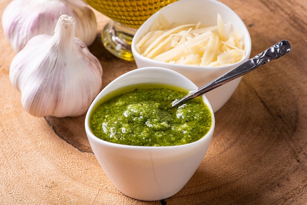 Sauce au pesto dans un bol avec les ingrédients en arrière-plan. Huile d'olive, ail et basilic.