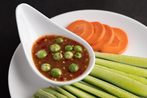 Sauce à la crevette dans un bol sur l'assiette blanche avec du concombre, des haricots et des carottes