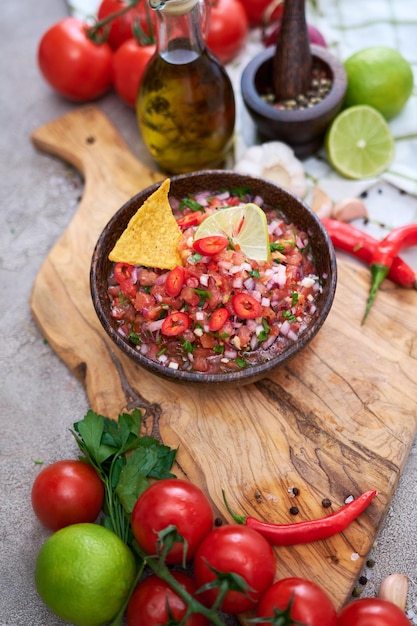 Sauce dip salsa fraîchement préparée avec chips nacho sur planche de bois