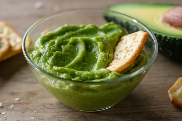 Sauce guacamole à l'avocat en purée dans un bol avec des craquelins