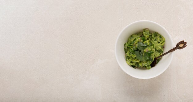 Sauce guacamole mexicaine dans un bol blanc sur un fond en béton, haut, espace copie