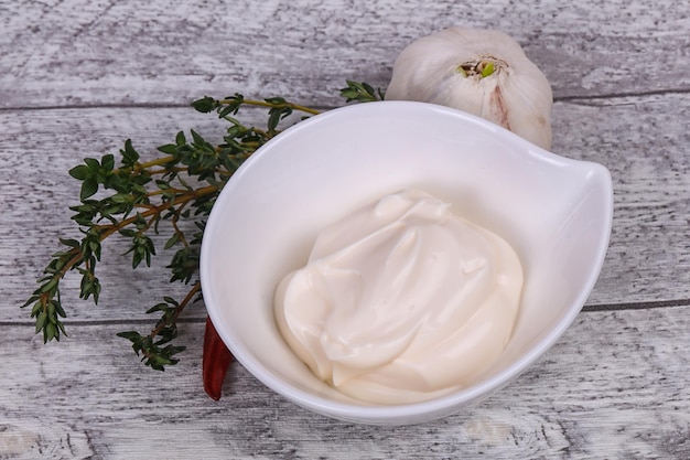 Sauce mayonnaise dans le bol blanc servi avec du thym et de l'ail