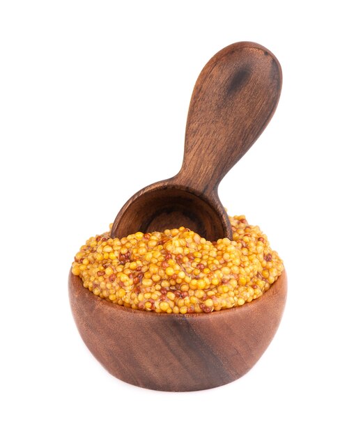 Sauce moutarde aux grains dans un bol en bois, haricots moutarde isolés.