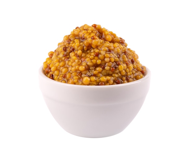 Sauce moutarde aux grains dans un bol, haricots moutarde isolés.