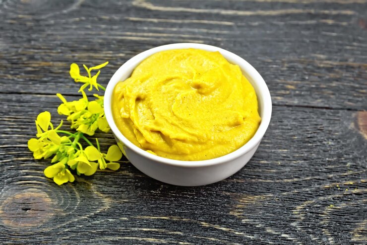 Photo sauce à la moutarde dans un bol blanc et fleur contre une planche en bois noire