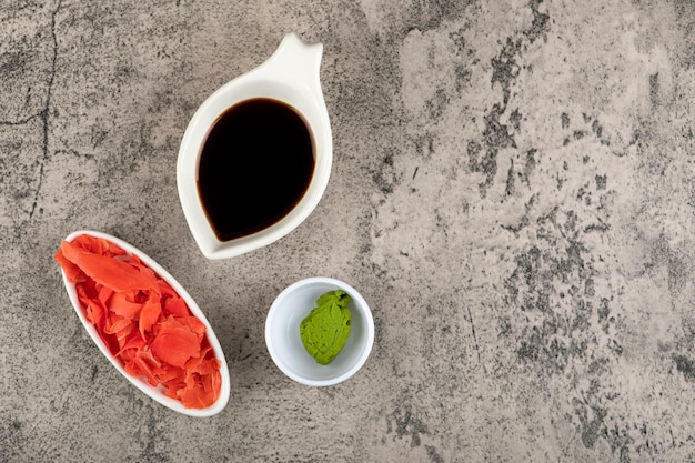 Sauce soja, gingembre mariné et wasabi sur table en pierre.