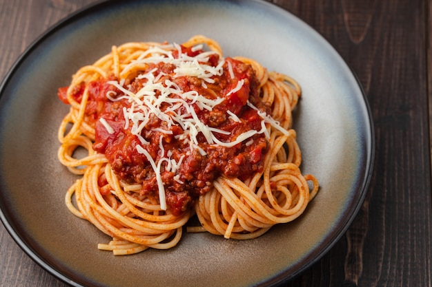 Sauce spaghetti bolognaise ou sauce tomate sur une planche de bois foncée
