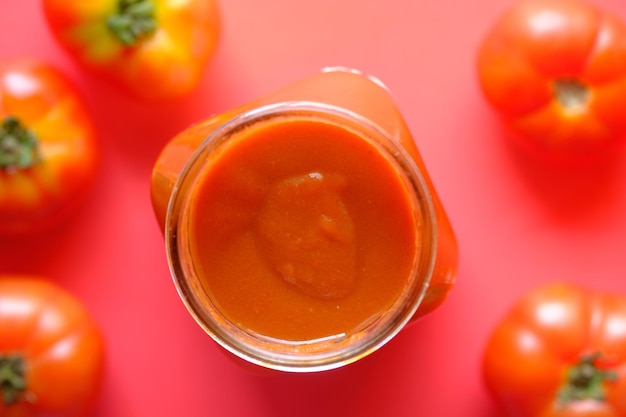 Sauce tomate dans un bocal avec tomates fraîches sur table