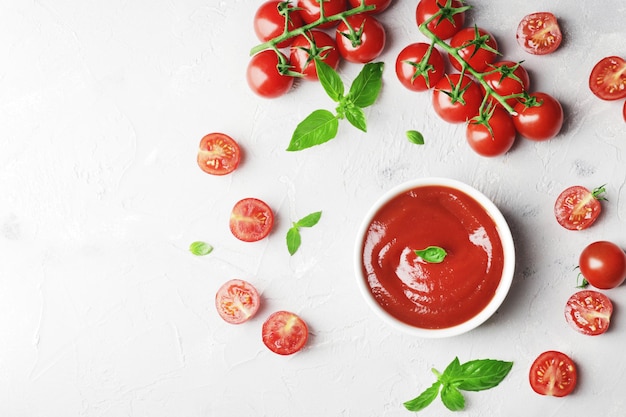 Sauce tomate dans un bol Basilic frais et tomates cerises fraîches Ingrédients pour la sauce Ingrédients pour la cuisson