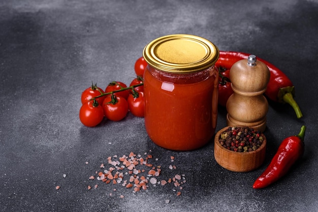 Sauce tomate douce épicée avec poivre à l'ail et herbes dans des bocaux en verre