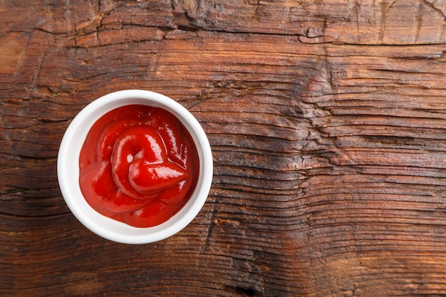 Saucière blanche avec du ketchup sur une table en bois