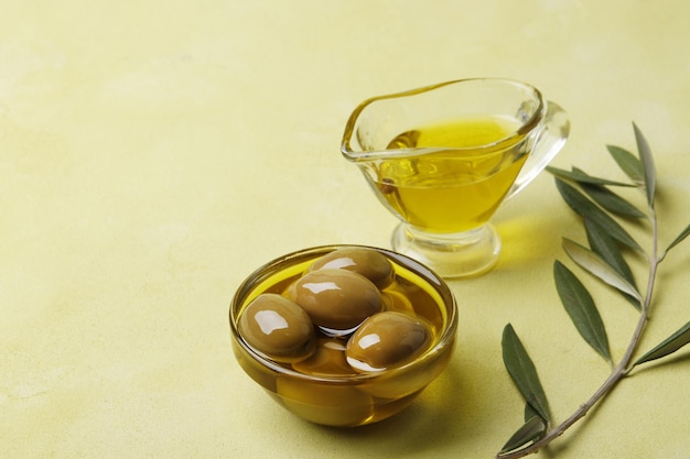 Saucière à l'huile d'olive, olives vertes et feuilles sur fond vert, vue de dessus