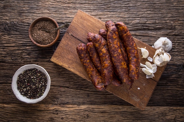 Photo saucises saucises fumées saucises chorizo avec des épices de romarin végétal et des ustensiles de cuisine