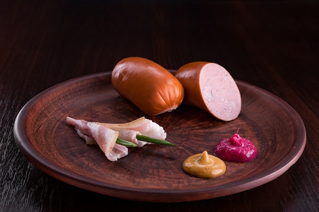 Saucisse avec apéritifs dans une assiette et sur une planche à découper.