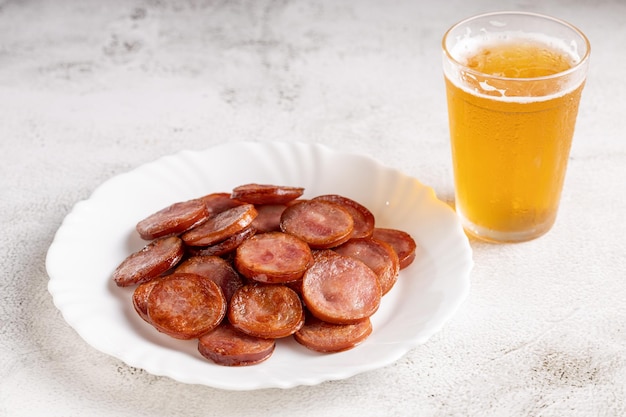 Saucisse au pepperoni frite en tranches avec un verre de bière sur la table