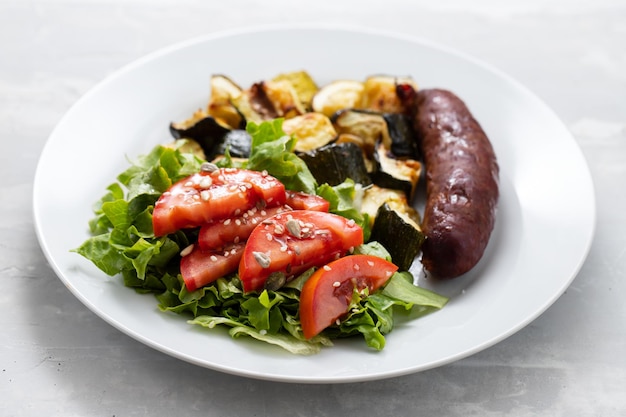 Saucisse aux légumes grillés et salade fraîche sur assiette