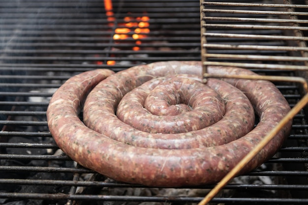 Une saucisse de bœuf sur un barbecue avec des charbons
