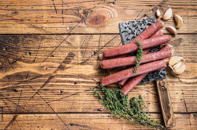 Saucisse de boeuf et de porc cru non cuit sur couperet à viande vintage. fond en bois.