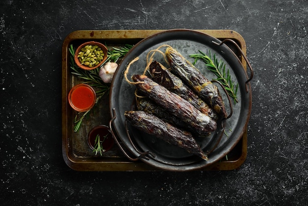 Saucisse de cheval traditionnelle faite maison. Saucisse aux épices sur fond de pierre noire. Vue de dessus. Espace libre pour le texte.