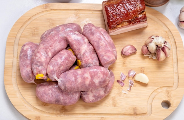 Saucisse crue sur une planche de bois, préparation, ingrédients