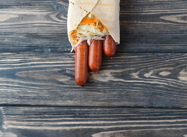 Saucisse fumée dans du pain pita sur fond de bois foncé photo avec espace de copie