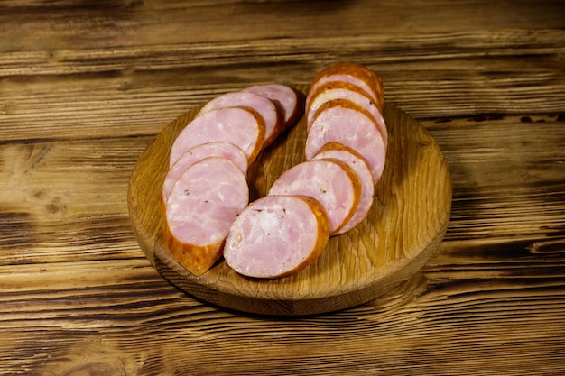 Saucisse fumée tranchée sur une planche à découper sur une table en bois