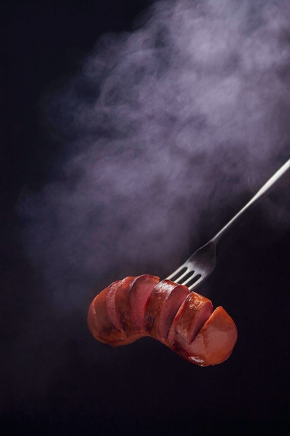 Saucisse grillée sur une fourchette avec photo sombre à la vapeur