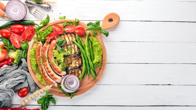 Saucisse grillée avec haricots aubergines et tomates sur le plateau Nourriture saine Sur une table en bois blanc Vue de dessus Espace libre pour le texte