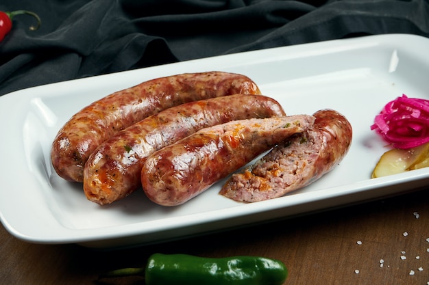 Saucisse hachée juteuse de porc grillé dans un fumoir avec du cheddar dans une assiette blanche avec des légumes en conserve. Collation de bière allemande