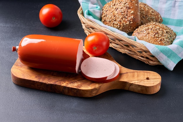 Saucisse de jambon bouilli tranchée sur une planche de cuisine en bois.