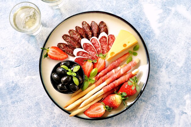 Saucisse, jambon, olives, fraises, câpres, tomates cerises sur une assiette