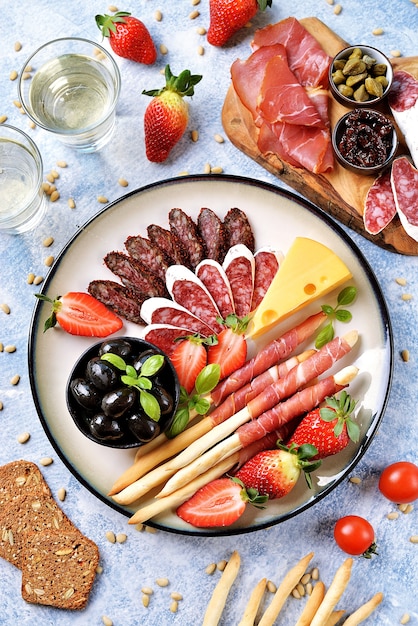 Saucisse, jambon, olives, fraises, câpres, tomates cerises sur une assiette