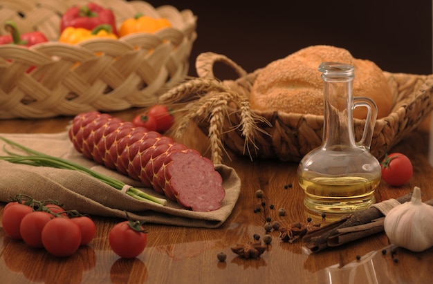 Saucisse et pain dans un panier en osier et légumes et ail sur une table