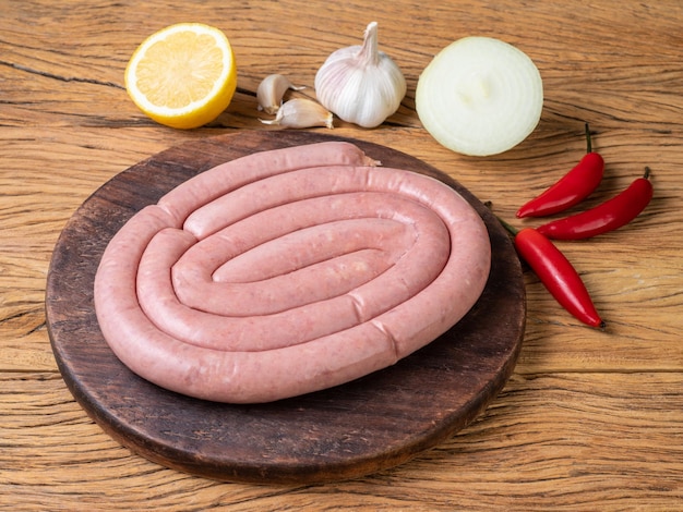 Saucisse de porc crue sur une planche de bois avec citron silicien et assaisonnements